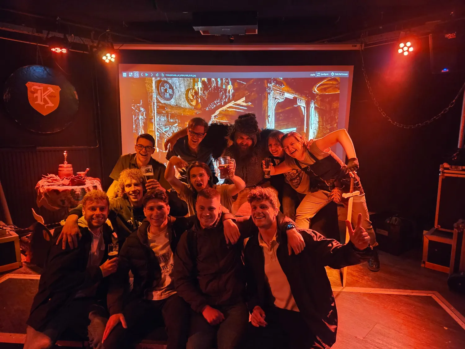Groep bezoekers en vrijwilligers in de warme podiumverlichting van K'77